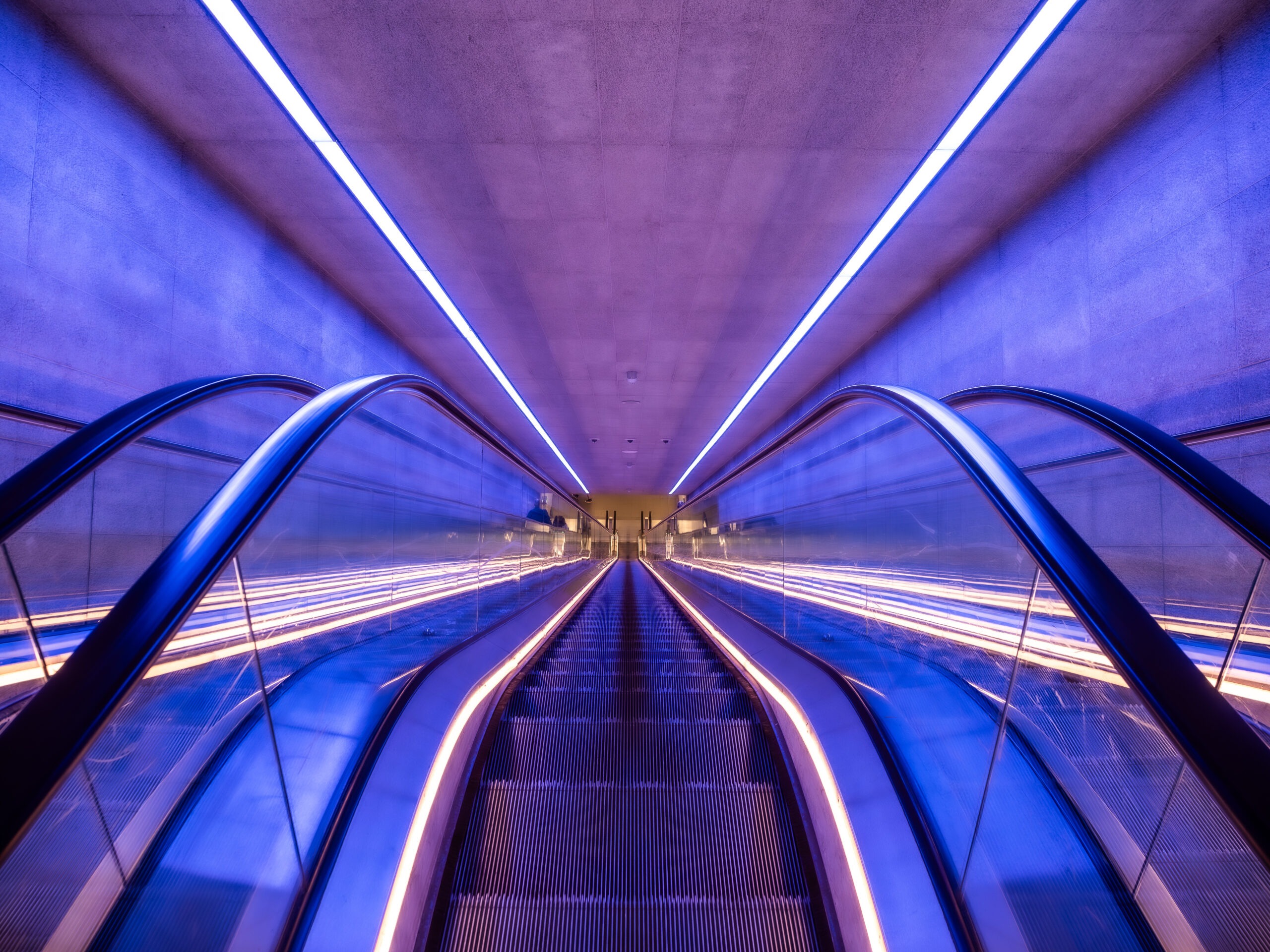 Blick die Rolltreppe einer U-Bahn-Station hinunter, viel blau und lila, Kopenhagen 2023